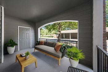 A balcony with a sofa, table, and potted plants.